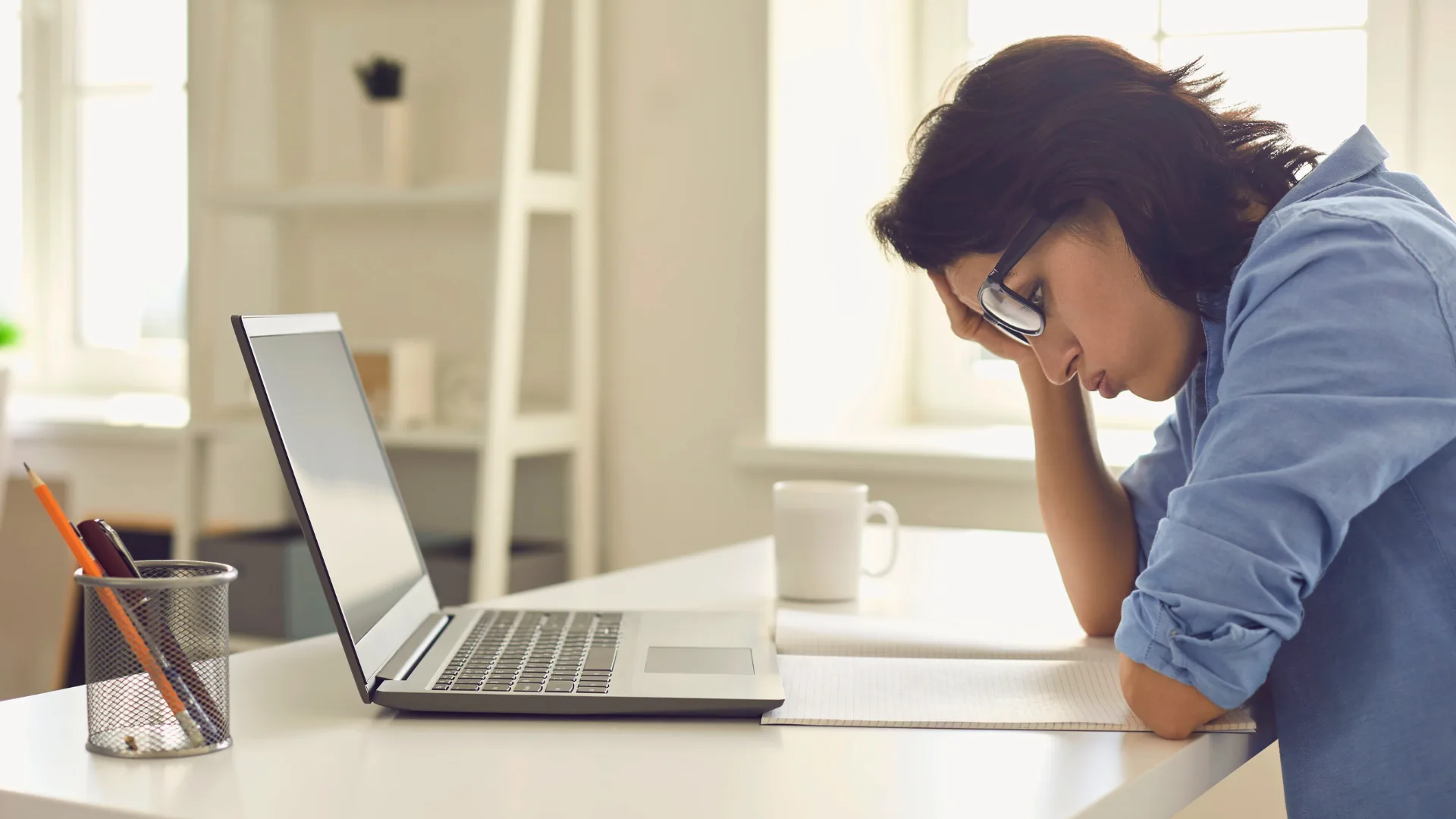 Produtividade ou armadilha? Os riscos de ignorar pausas no home office 1 Mulher mentalmente exausta no home office, diante do computador, devido ao excesso de trabalho sem pausas.