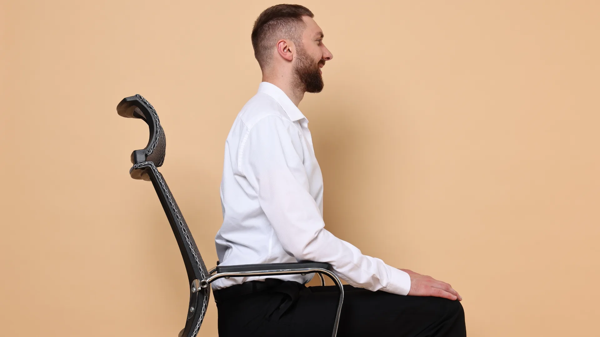 3 itens pouco comentados que estão transformando o home office de quem trabalha sério 1 Homem com postura correta sentado em cadeira ergonômica com apoio lombar, em ambiente neutro e confortável de trabalho, itens